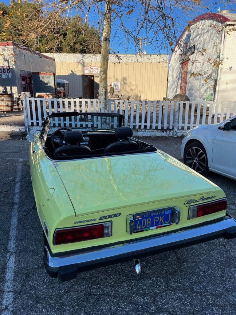 Classic yellow convertible car parked outdoors on a sunny day.