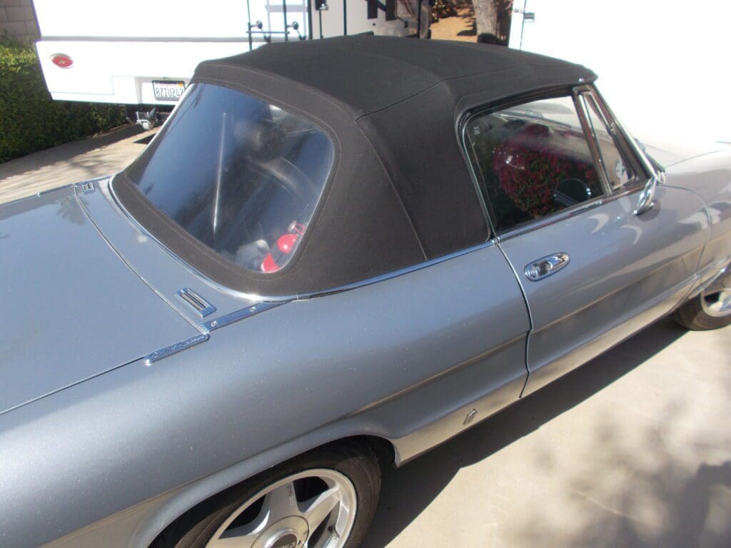 Classic silver convertible car with a black soft top roof.
