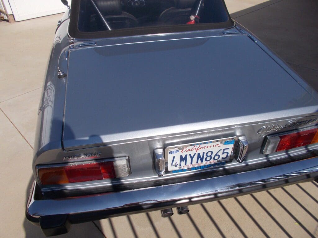 Silver car parked on a sunny street with a visible license plate.