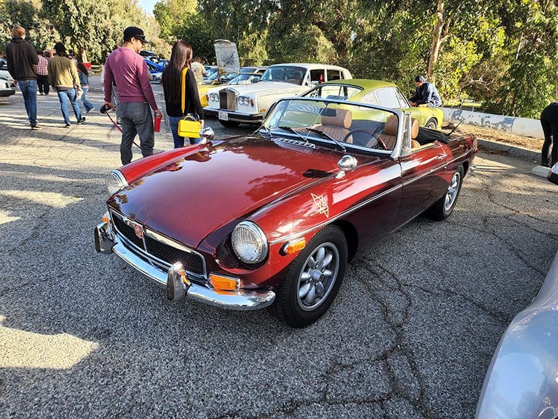 Classic red convertible car parked at an outdoor event.