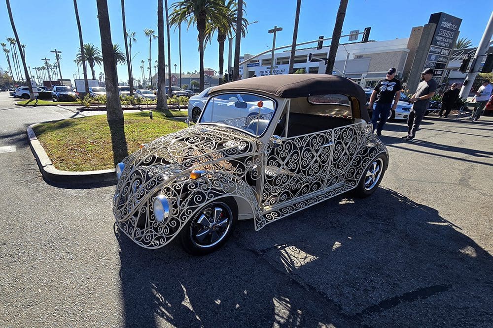 Custom vintage car with intricate wireframe design parked outdoors.