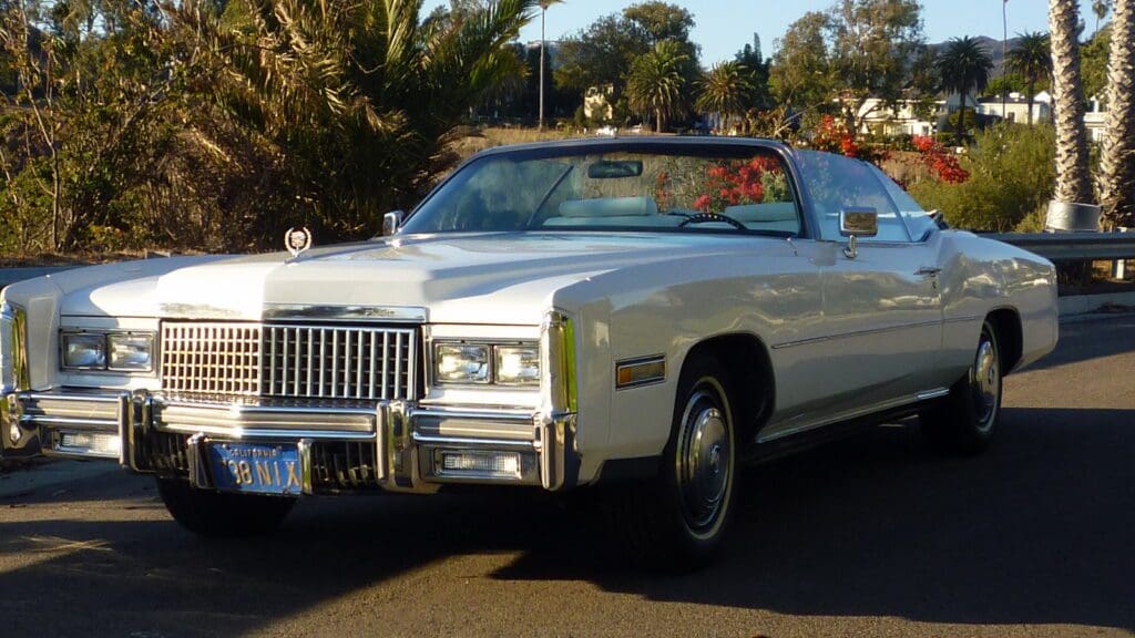 A classic white convertible car parked on a sunny street.