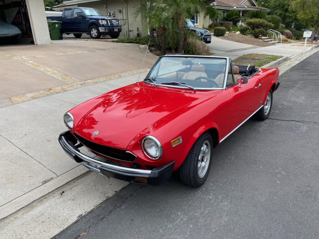 Red classic convertible car parked on a suburban street.