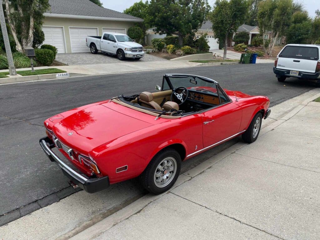 Red classic convertible car parked on a suburban street.