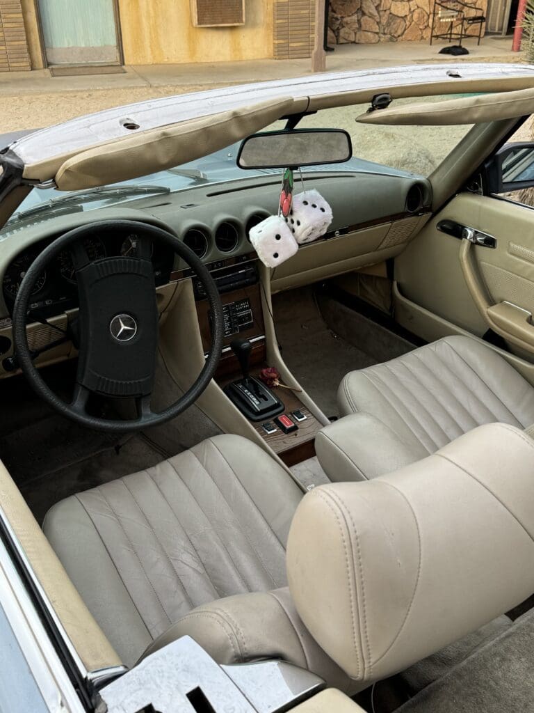 Interior of a vintage car with beige seats and a classic dashboard.