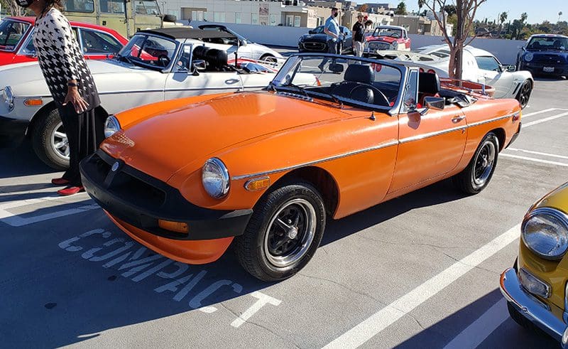 Bright orange classic convertible car parked on a sunny day.