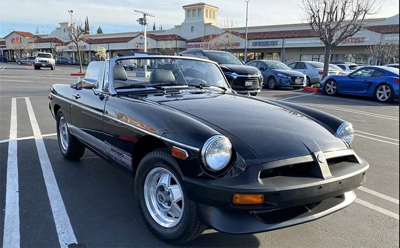 Classic black convertible car parked outdoors with a clear sky.