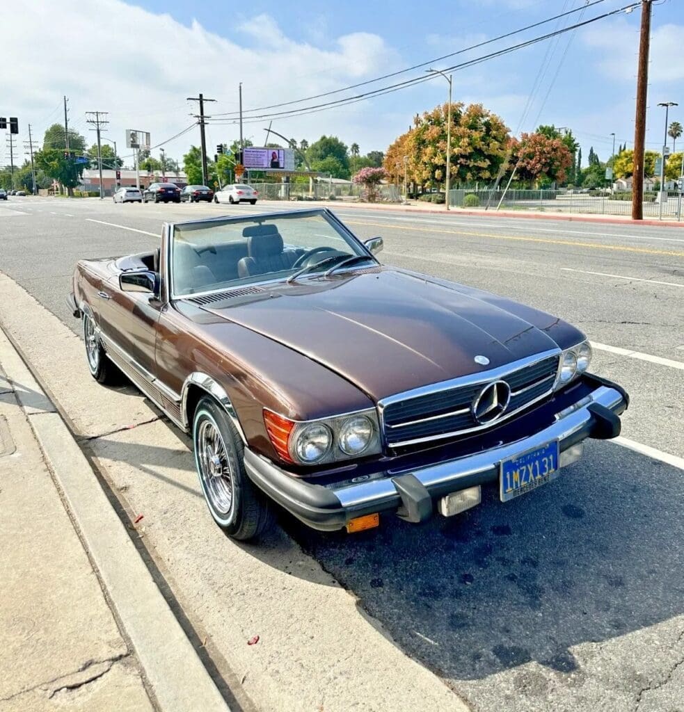 Classic brown Mercedes convertible parked by the roadside on a sunny day.