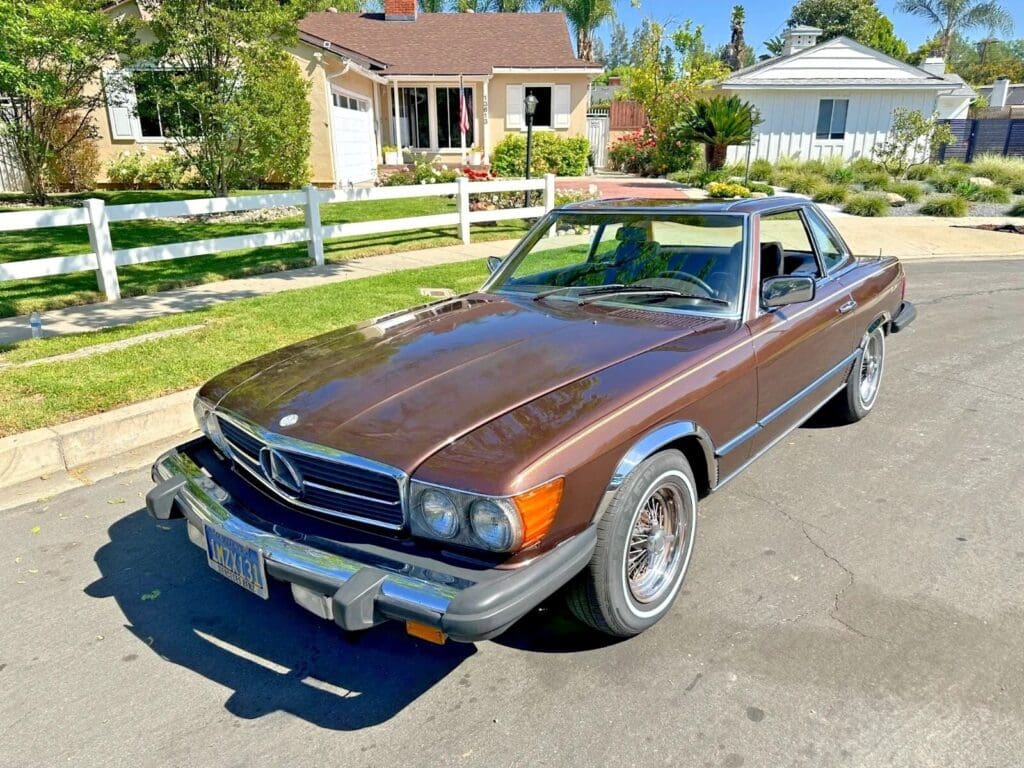 Classic brown Mercedes convertible parked on a sunny suburban street.