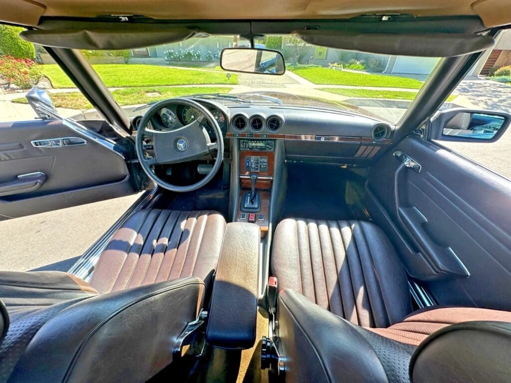 Vintage car interior with black leather seats and classic dashboard.