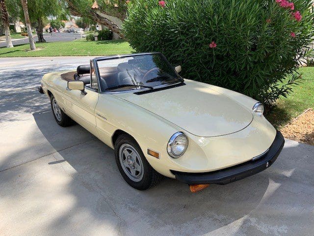 Classic yellow convertible car parked on a driveway.