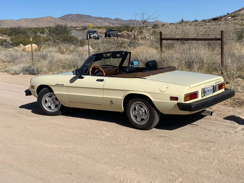 Classic yellow convertible car parked on a driveway.