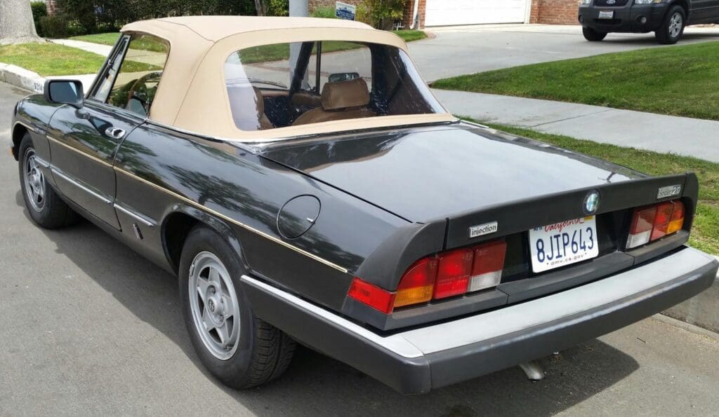 Classic convertible car with a soft top in a driveway.