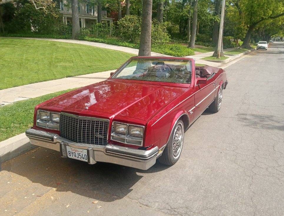 A classic red convertible car parked on a suburban street.