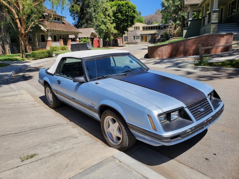 Classic silver sports car parked in a sunny residential area.