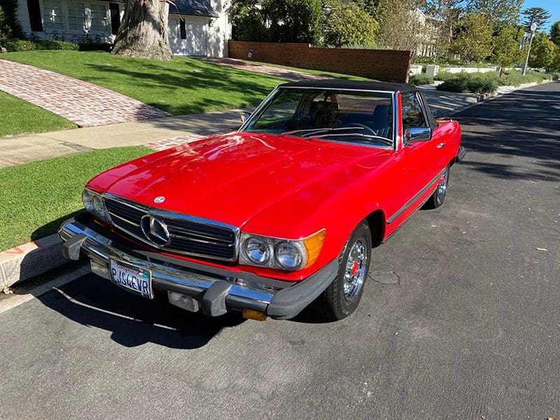 Classic red Mercedes convertible parked on a sunny driveway.