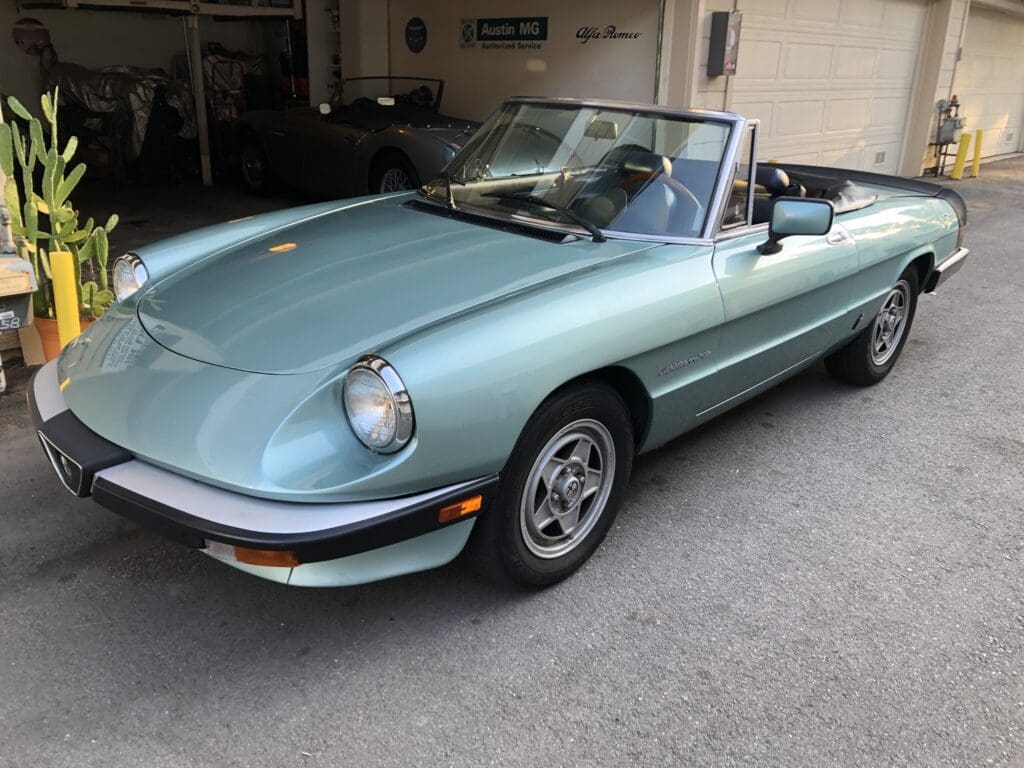 Classic light blue convertible sports car parked in a garage.