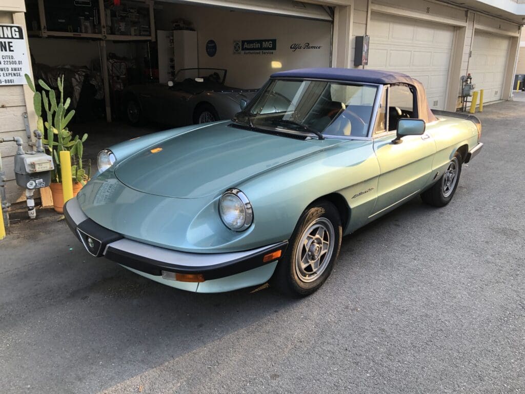 Classic light blue convertible car parked in a driveway.