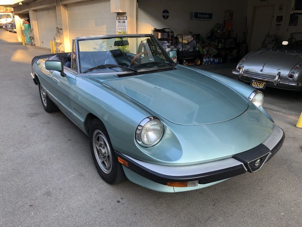 Light blue classic convertible car parked in a garage.