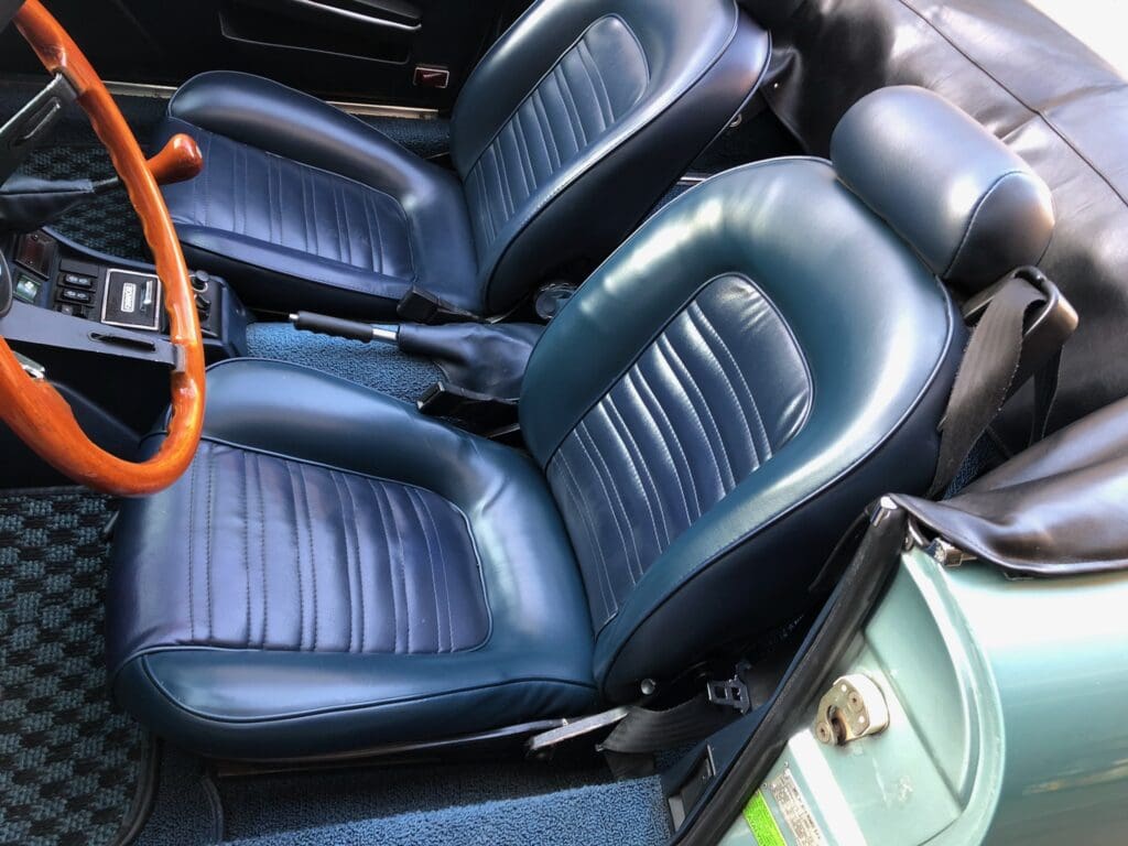 Close-up of black leather car seats with detailed stitching.