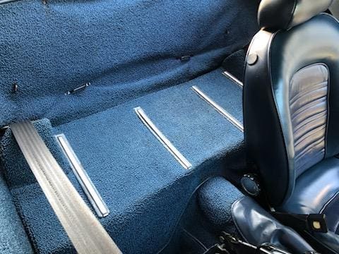 Blue carpeted interior of a car with metal strips on the floor.