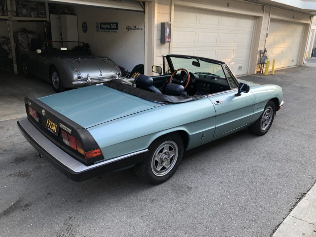 Classic light blue convertible car parked in a garage.