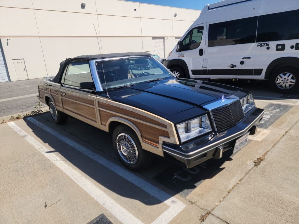 Classic black convertible car parked in a sunny lot.