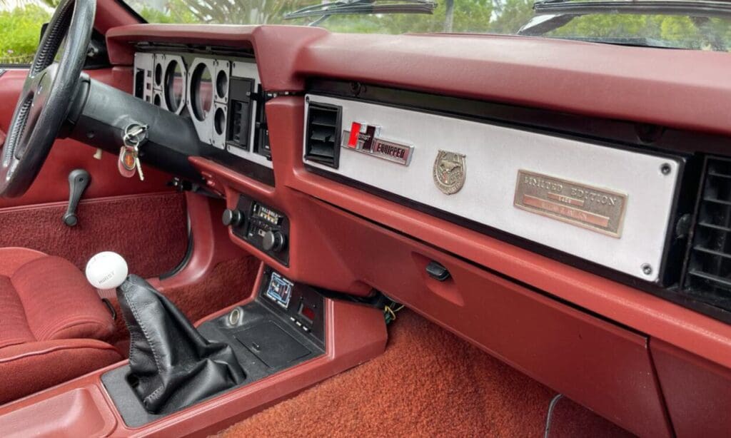 Close-up of a vintage car's red dashboard and gear shift.