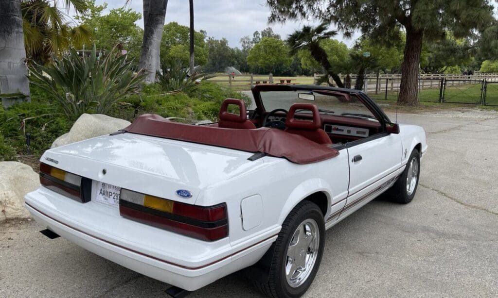White convertible car with maroon interior parked outdoors.