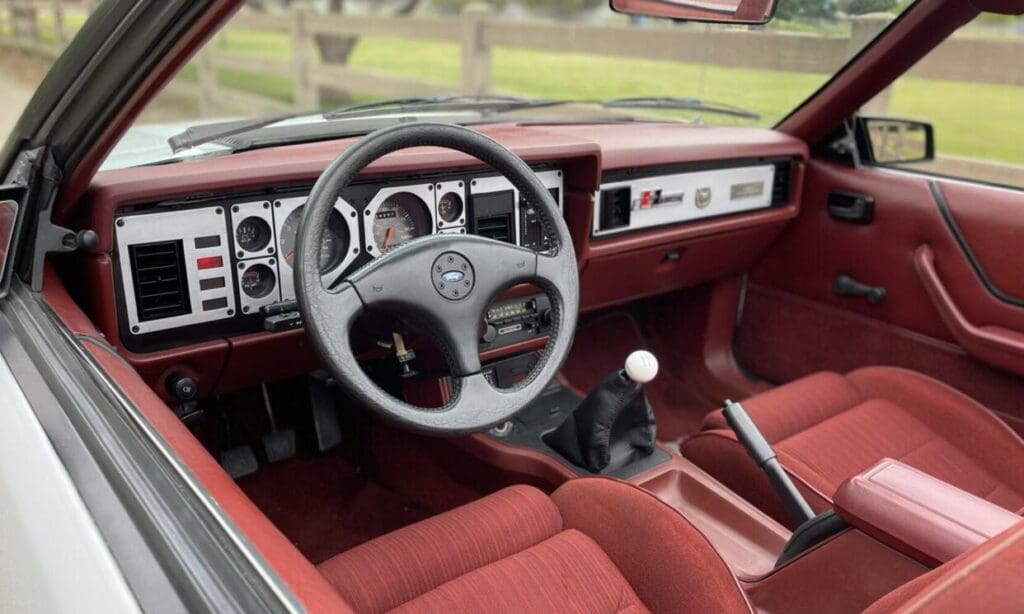 Classic car interior with red upholstery and a manual transmission.