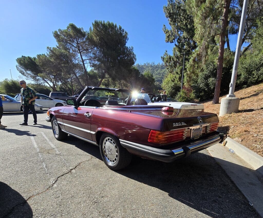A vintage red convertible car parked outdoors on a sunny day.