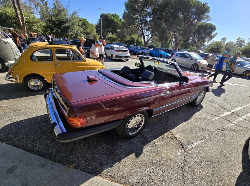 Classic maroon convertible car parked outdoors on a sunny day.