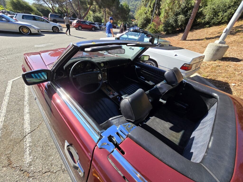 Convertible car with a damaged windshield and blue tape on the hood.