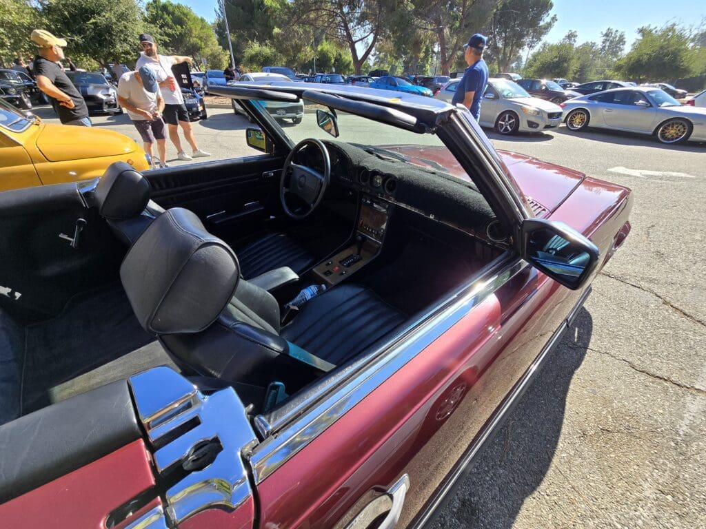 Classic convertible car parked at a sunny outdoor car show.