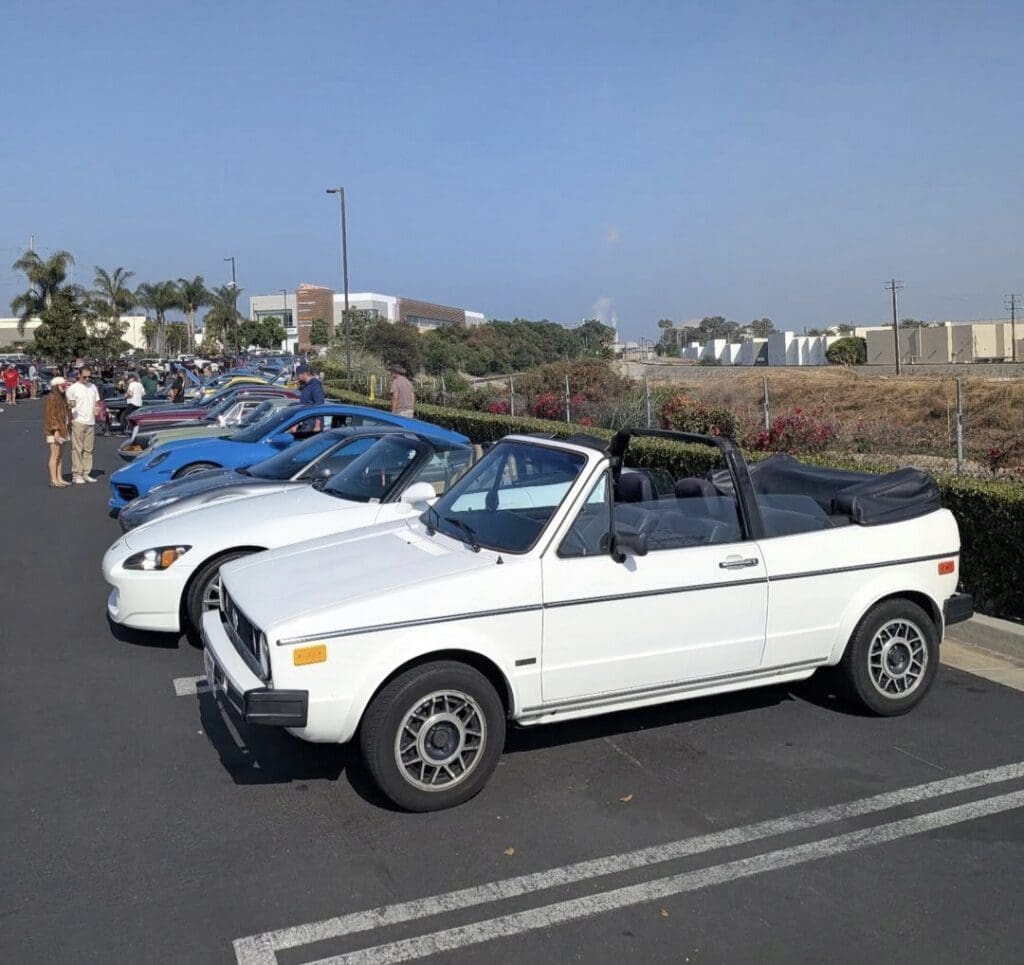 A lineup of vintage and modern cars parked outdoors on a sunny day.