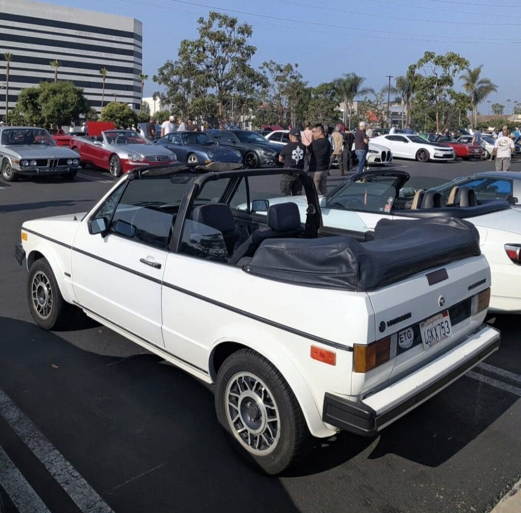 Classic white convertible car parked at an outdoor event.