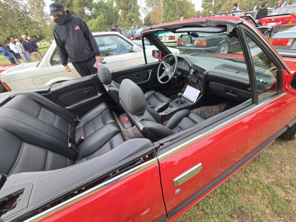 Red convertible car with black leather interior parked outdoors.