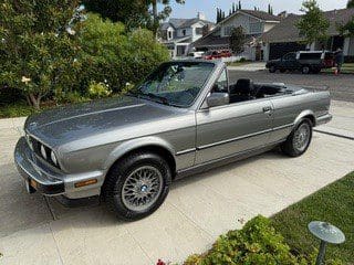 Silver convertible car parked in a residential driveway.