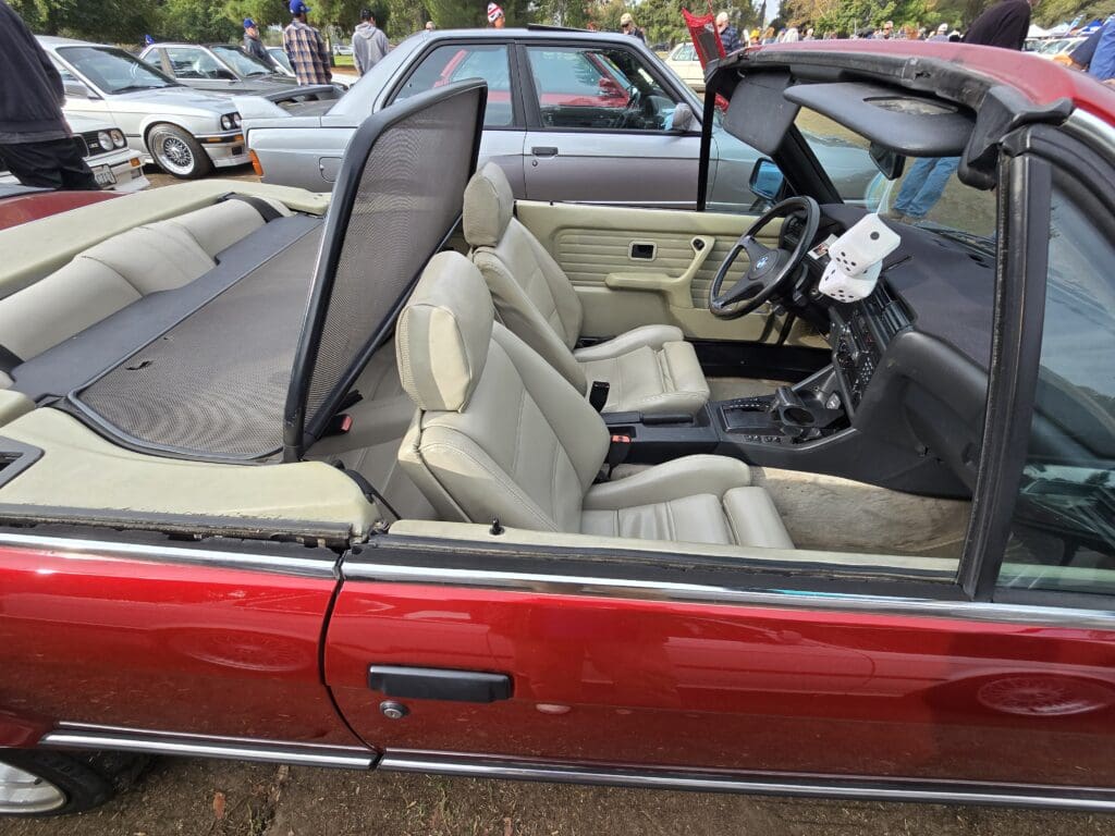 Classic red convertible car with beige leather interior and open roof.