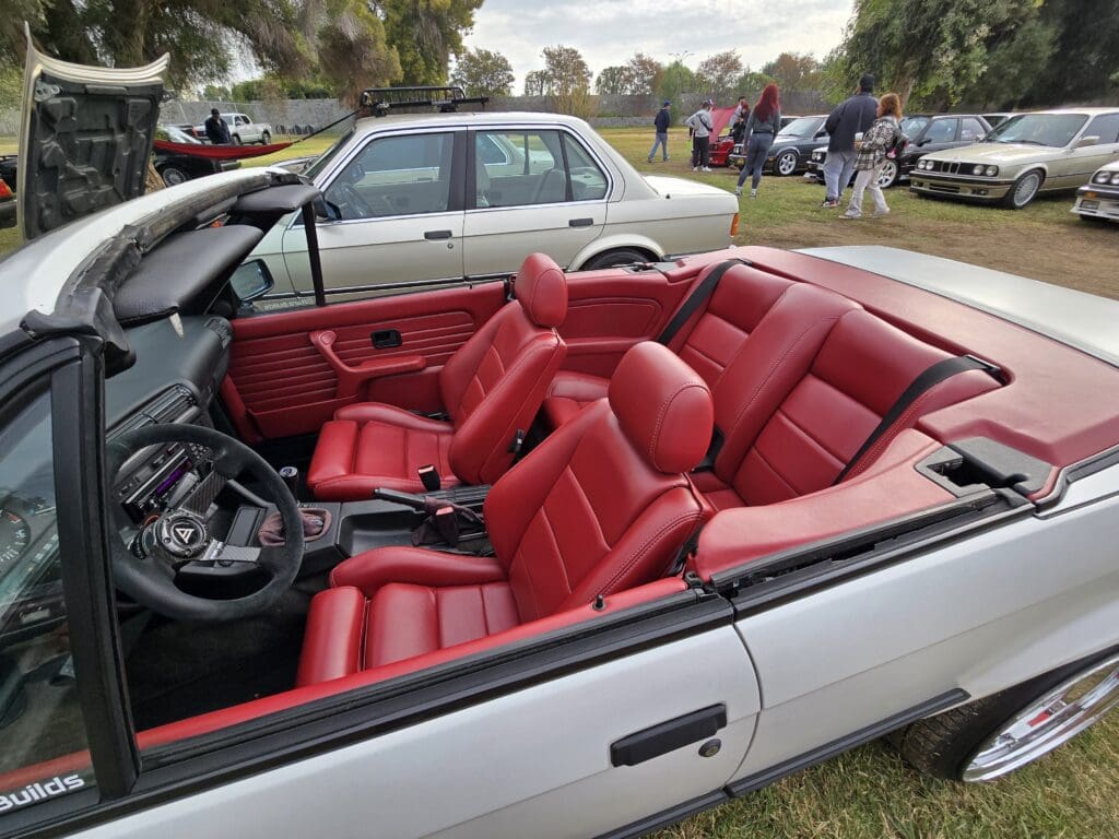 Convertible car with vibrant red leather interior parked outdoors.