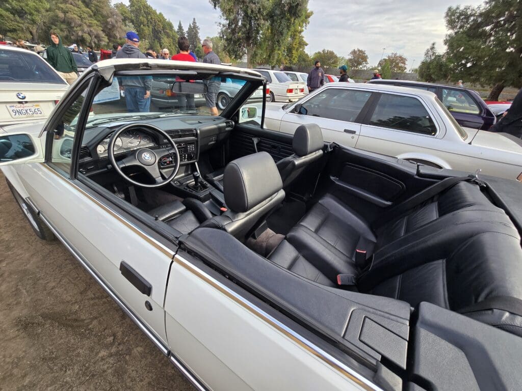 Interior view of a classic white convertible car with black leather seats.