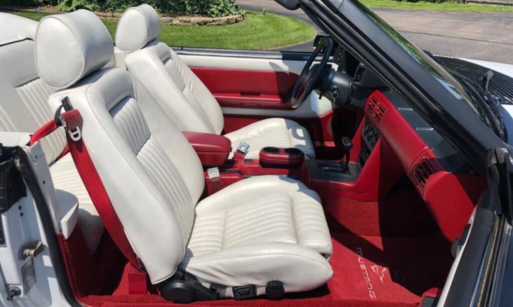 Interior of a red convertible car with white leather seats.