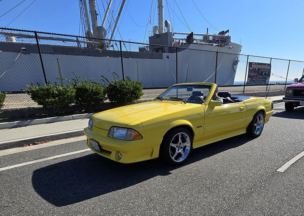 Yellow convertible sports car parked by the roadside on a sunny day.