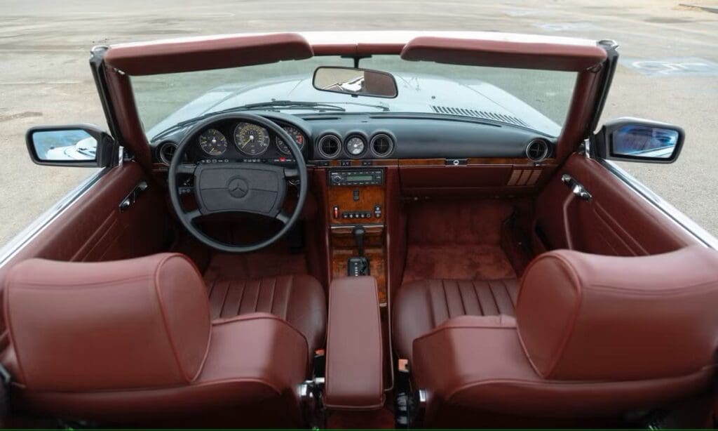 Interior of a classic car with brown leather seats and wooden dashboard accents.