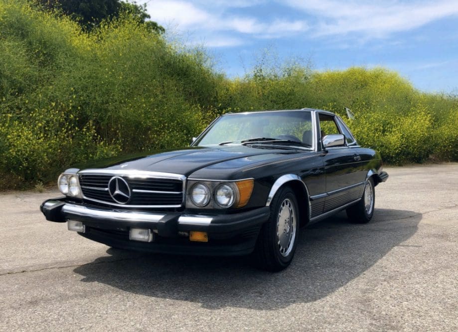 Classic black Mercedes-Benz convertible parked on a sunny road.