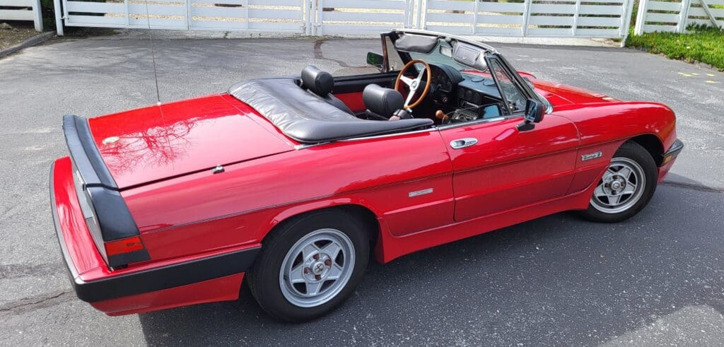 Red vintage convertible car with black interior and open roof.