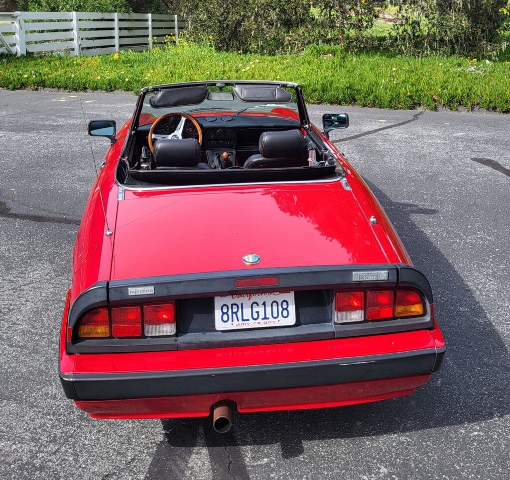 Red convertible sports car parked on a driveway with the top down.