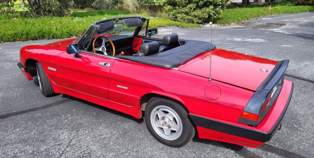 Red convertible sports car parked outdoors with its top down.
