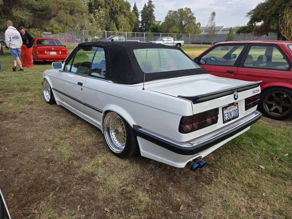 White convertible car with black soft top and sporty modifications.