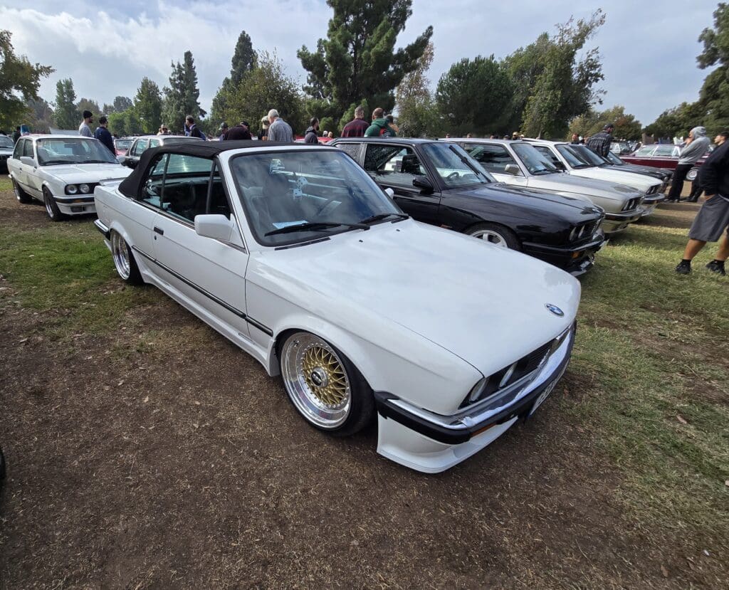 Classic white BMW convertible parked outdoors among other vintage cars.